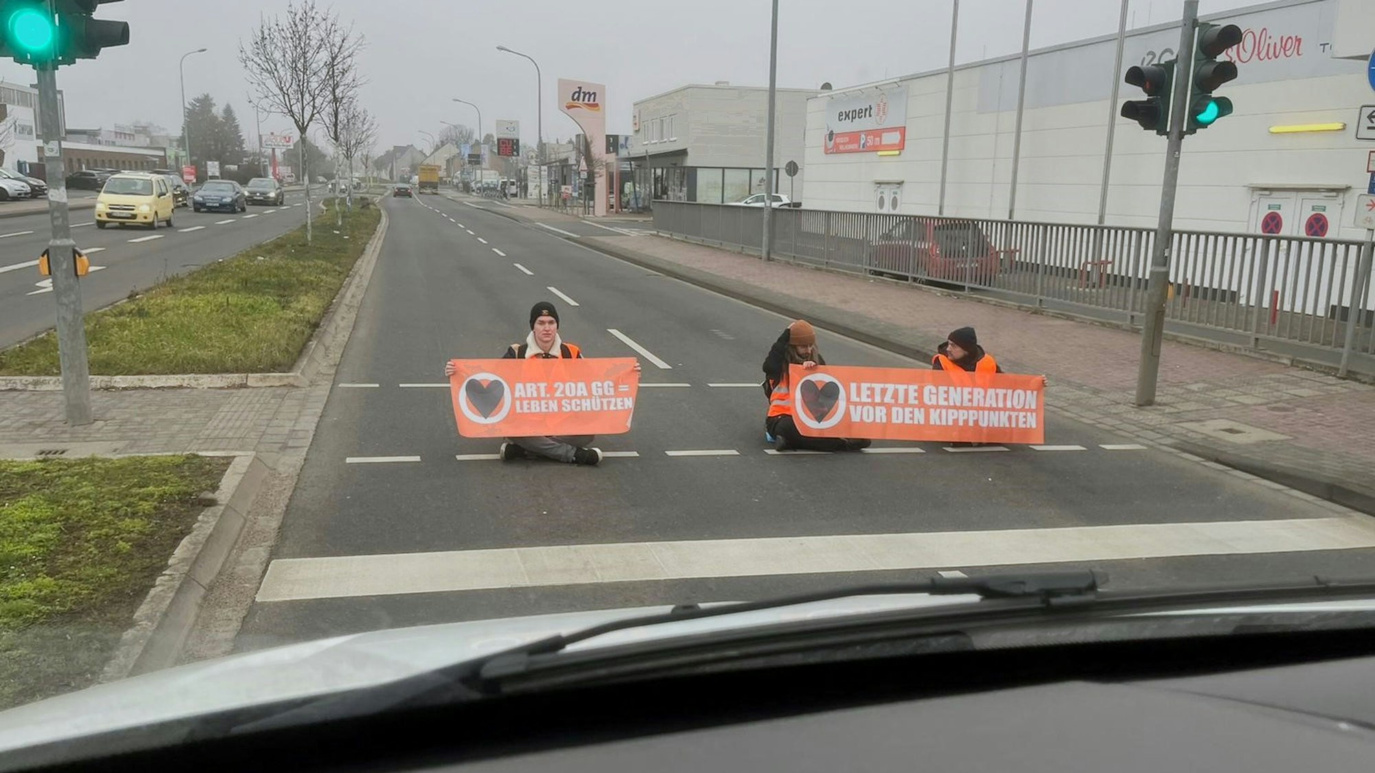 Drei Männer mit Plakaten der Gruppe „Letzte Generation“ wollten sich auf der Roitzheimer Straße in Euskirchen festkleben.