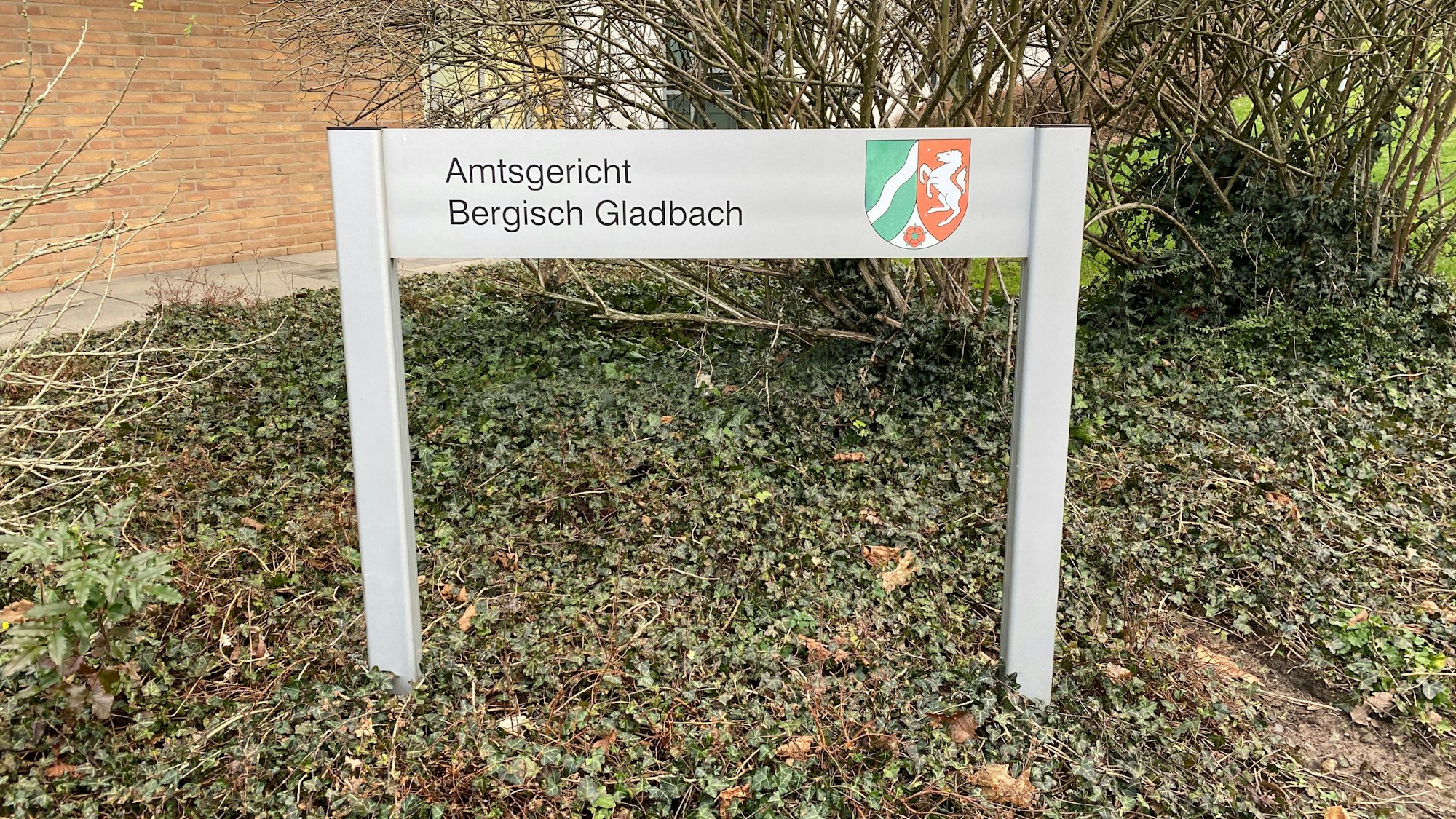 Vor dem Amtsgericht steht ein Schild mit der Aufschrift Amtsgericht Bergisch Gladbach.