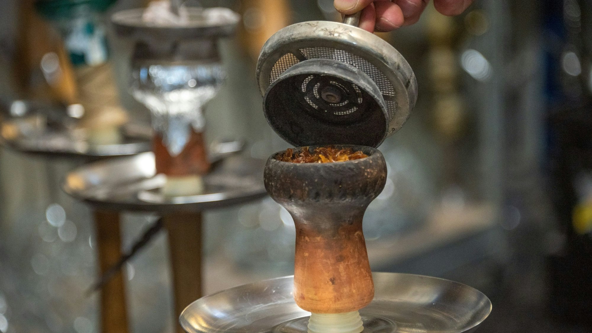 Ein Mitarbeiter füllt in einer Shisha-Bar Tabak in den Kopf der Pfeife.