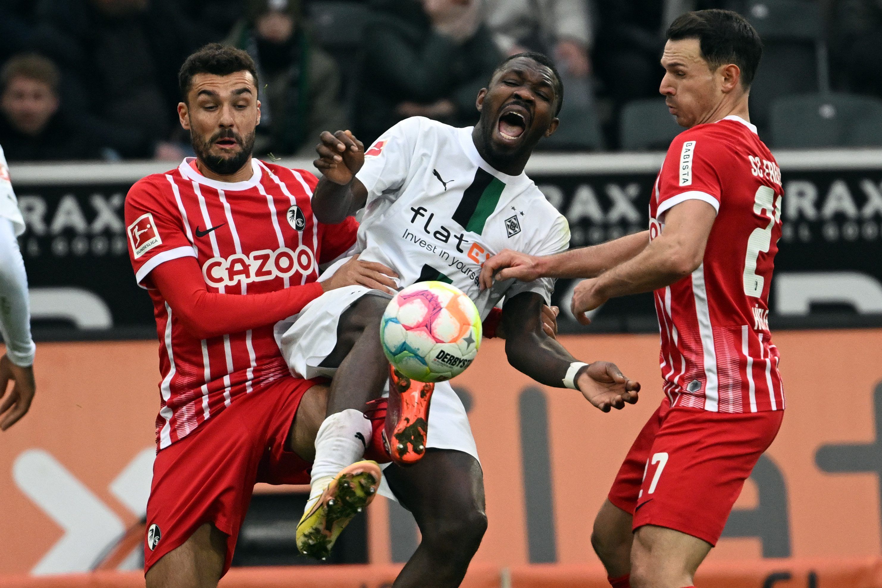 Gladbachs Marcus Thuram (M) und Freiburgs Manuel Gulde (l) und Nicolas Höfler kämpfen um den Ball.