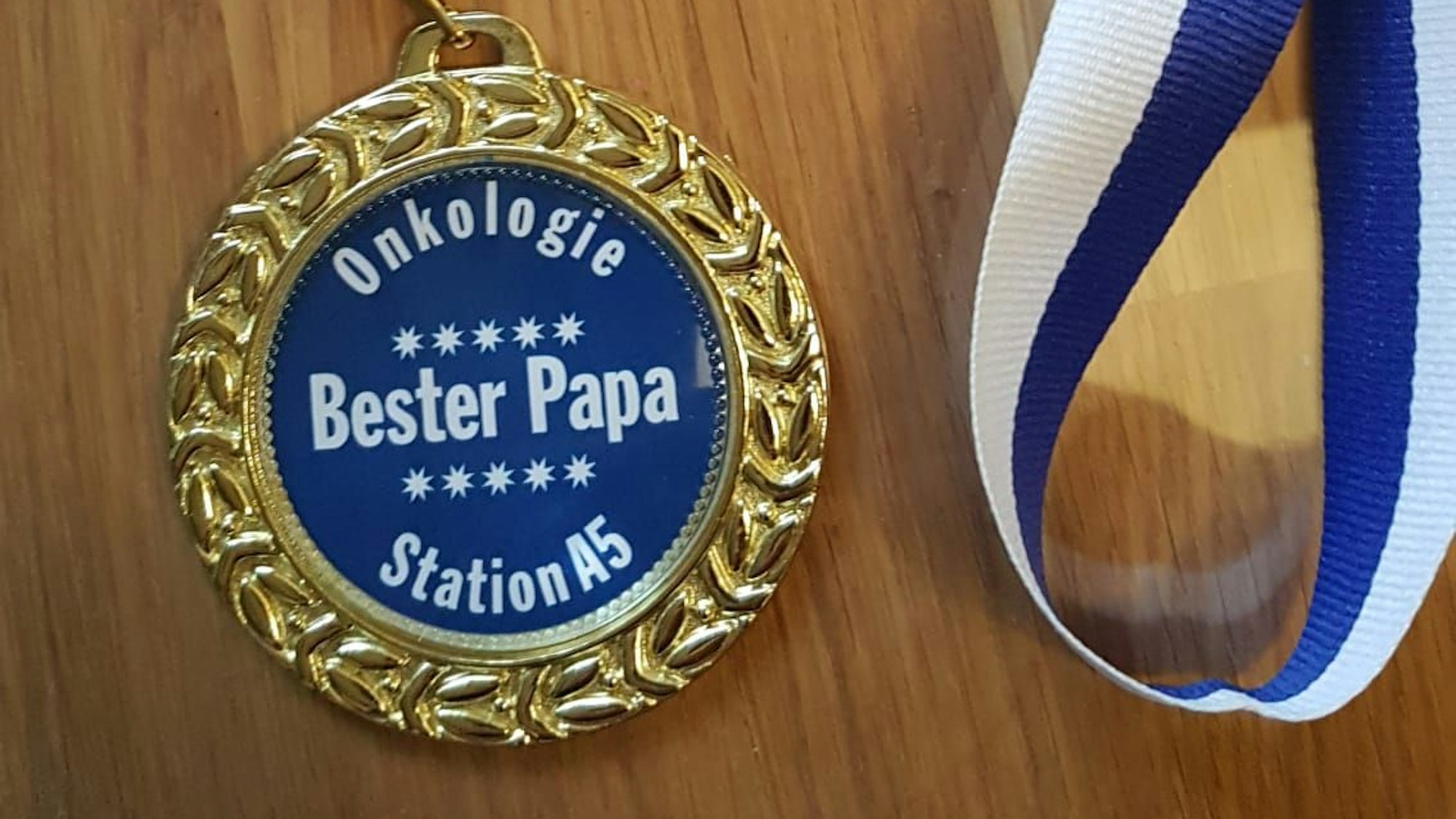 Ein Orden mit der Aufschrift „Onkologie – Station A5 – Bester Papa “ liegt auf einem Tisch.
