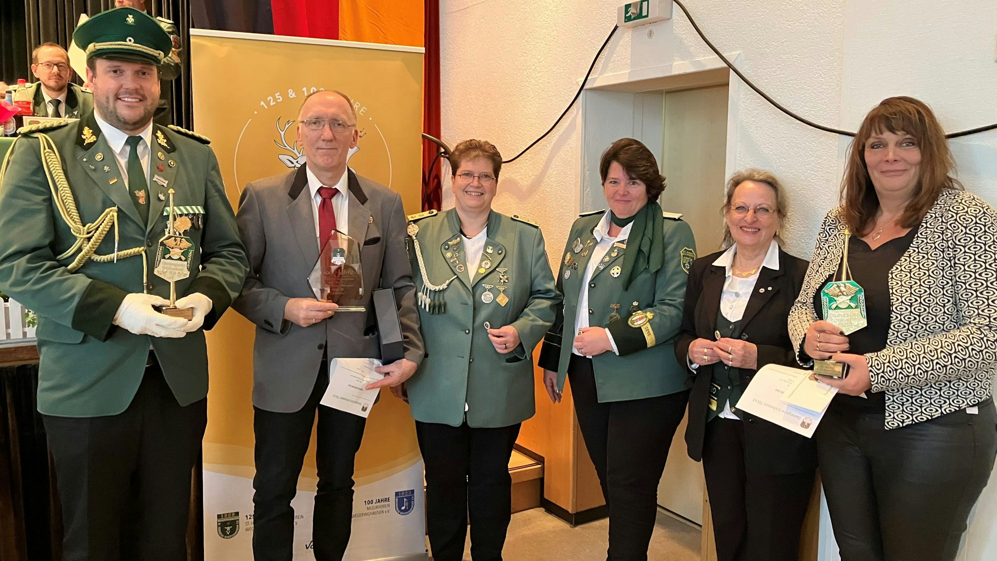 Mehrere Frauen und Männer in Schützenkleidung stehen mit Urkunden und Wimpeln in der Hand nebeneinander.