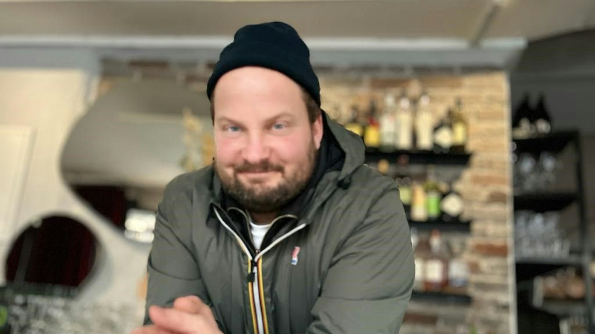 Gabriel Zanchetti trägt eine dunkle Mütze, im Hintergrund befindet sich eine Bar.