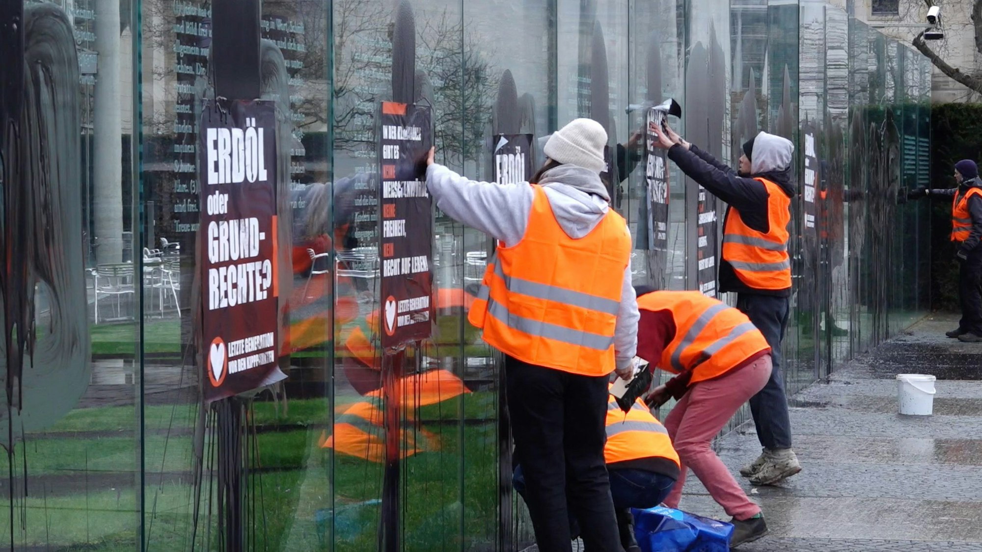 Klimaaktivisten der „Letzten Generation“ beschmieren und plakatieren am Samstag die gläserne Grundgesetz-Skulptur am Bundestag.