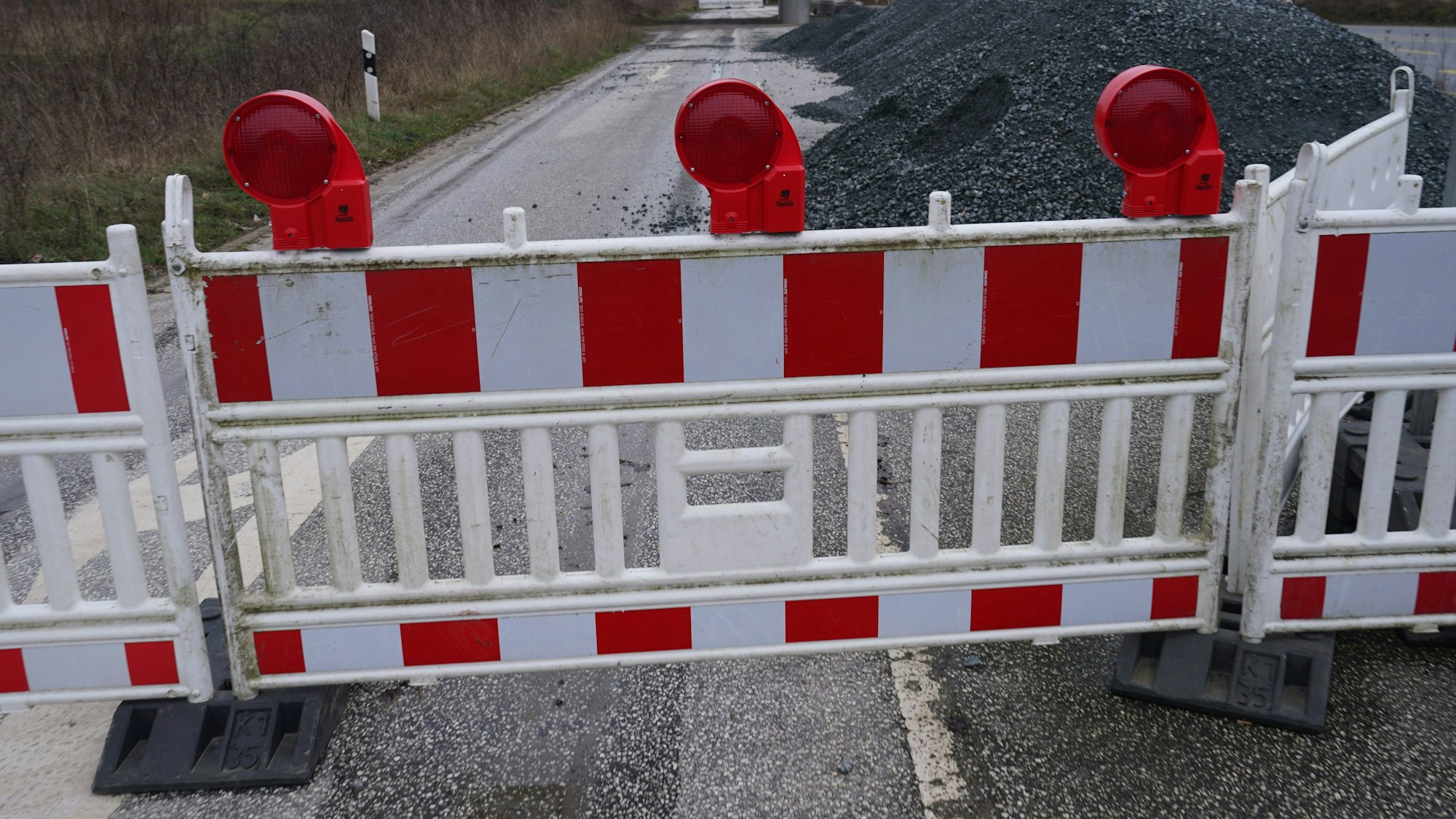 Ein Baustellenzaun versperrt die Durchfahrt einer Straße.