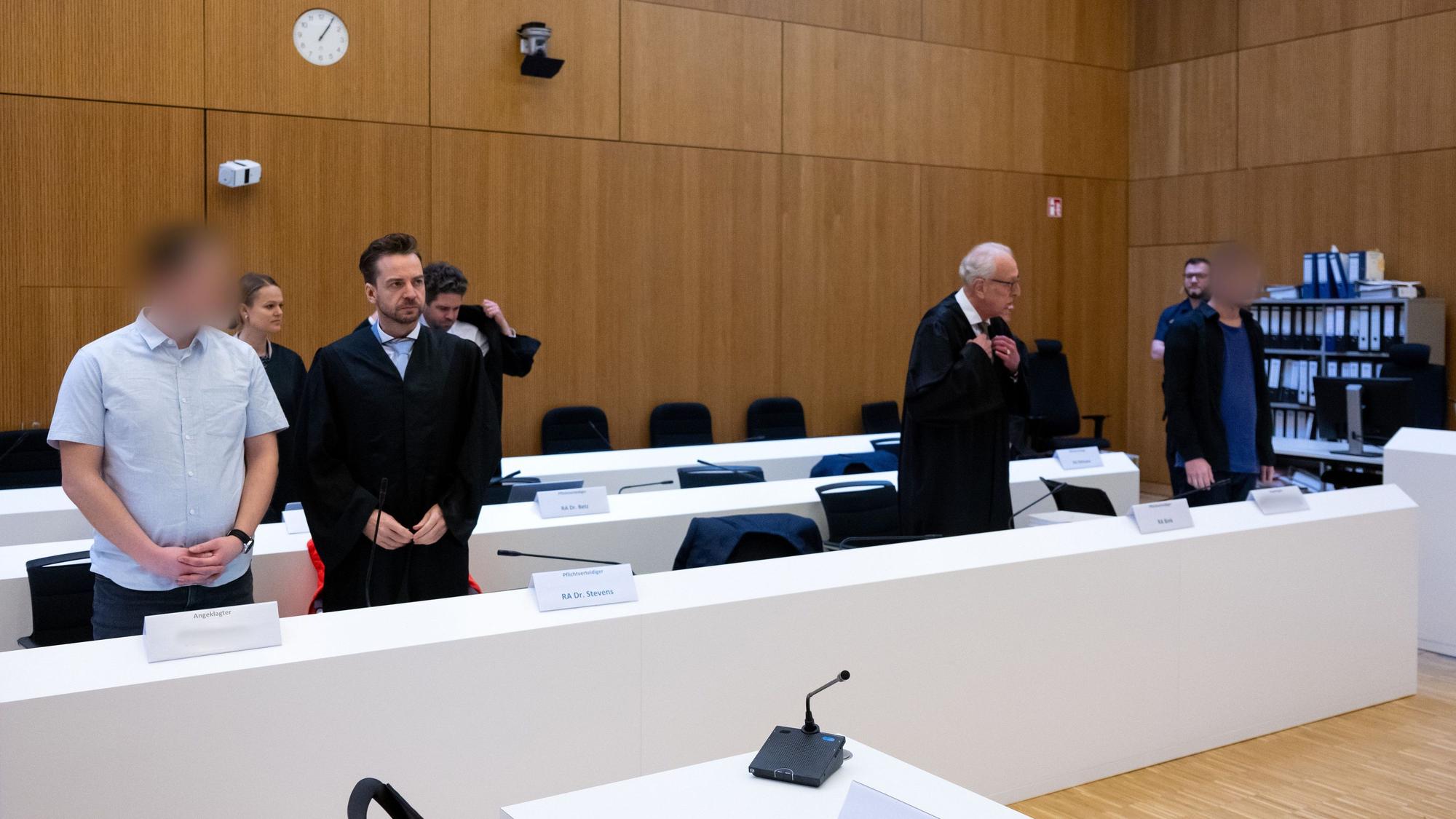 Die zwei wegen Mordes angeklagten Männer stehen vor Beginn der Verhandlung neben ihren Rechtsanwälten.