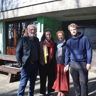 Die Familie steht vor dem Eingang eines Hauses und schaut in die Kamera.