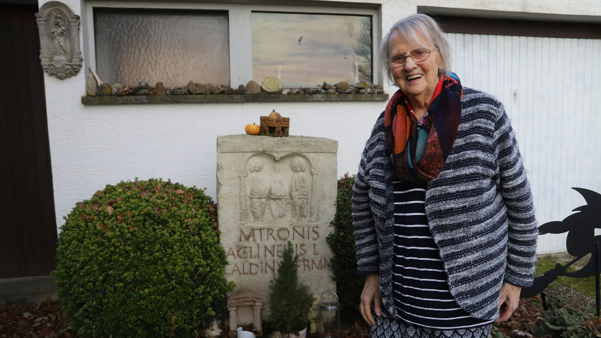Sophie Lange neben einem Matronen-Stein, hinter ihr ein Haus.
