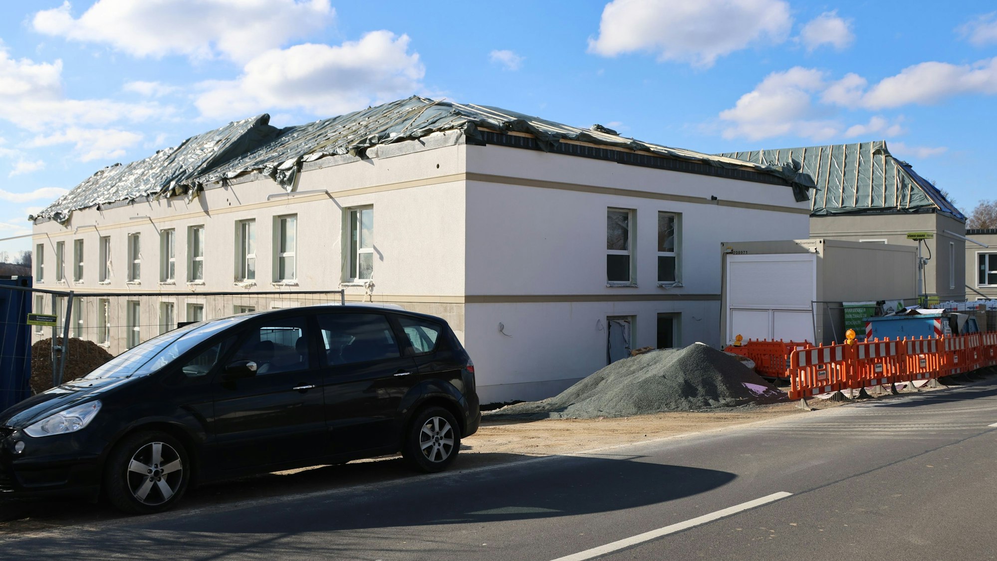 Ein unfertiges Haus im Bau, mit Plane auf dem Dach.