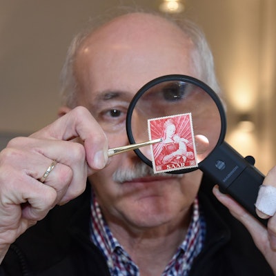 Der Sammler Friedrich Dörre nimmt eine Briefmarke unter die Lupe.