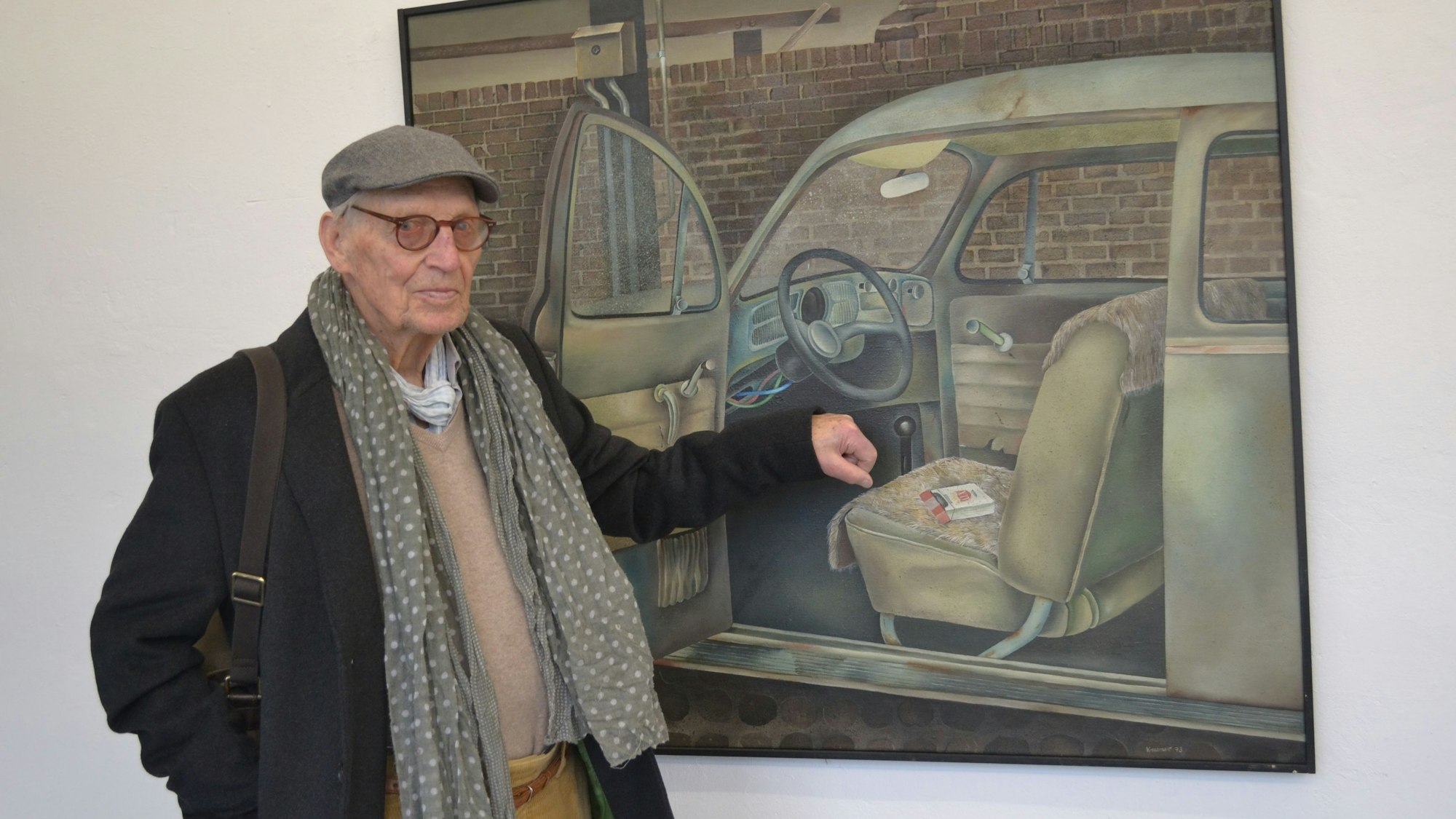 Der Künstler steht vor einem Bild eines Käfers.