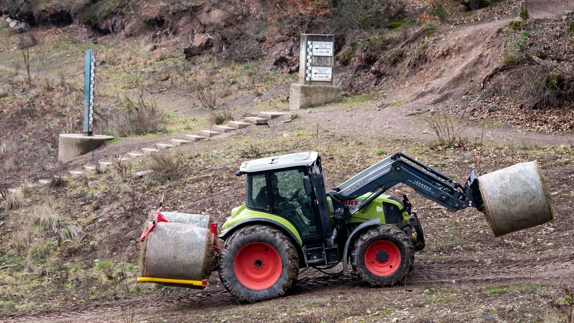 Mit einem Traktor holt ein Spezialunternehmer die gepressten Ballen nach und nach aus der Talsperre.