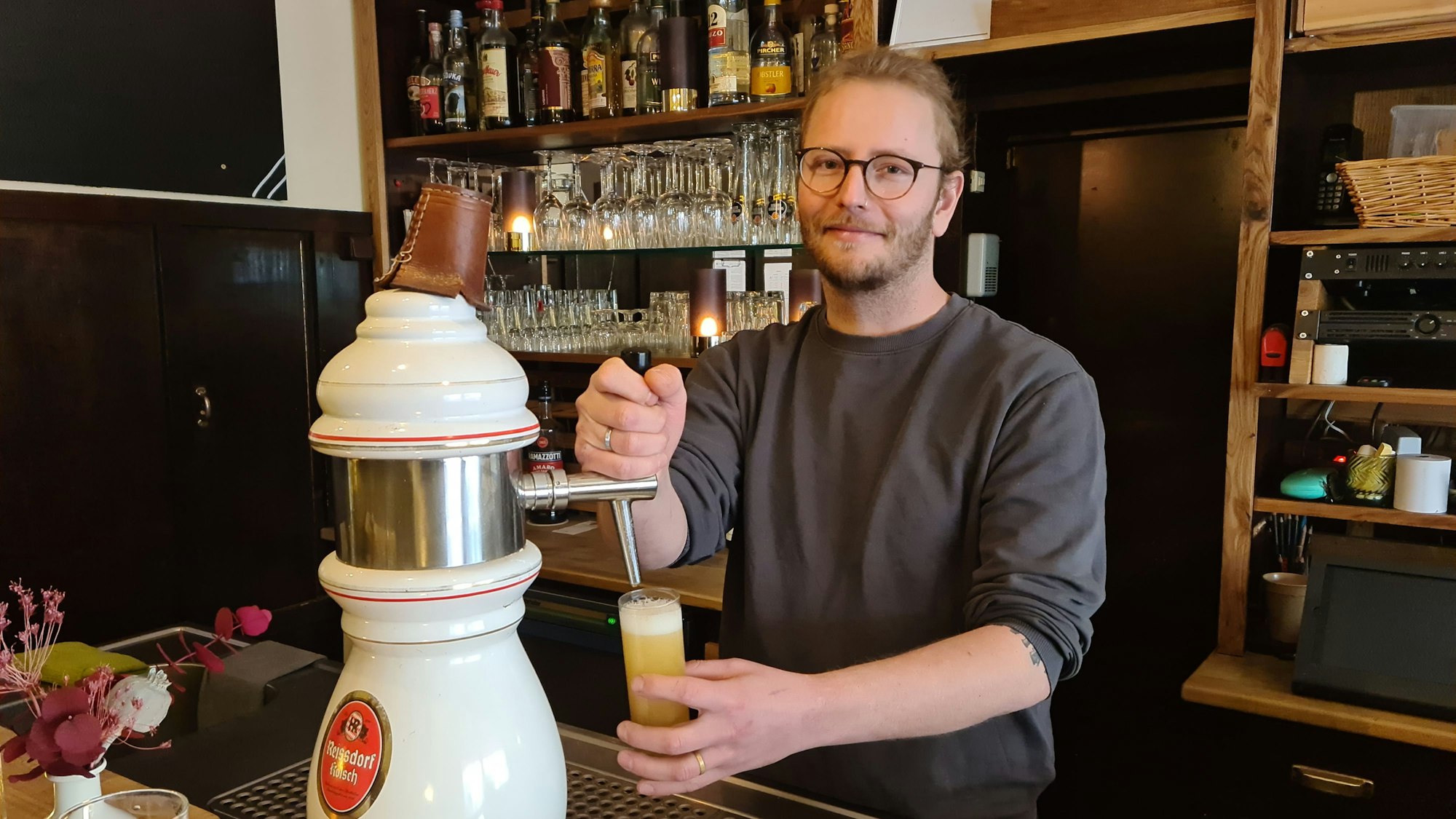 Tim Rosnau steht hinter der Bar und zapft ein Bier.