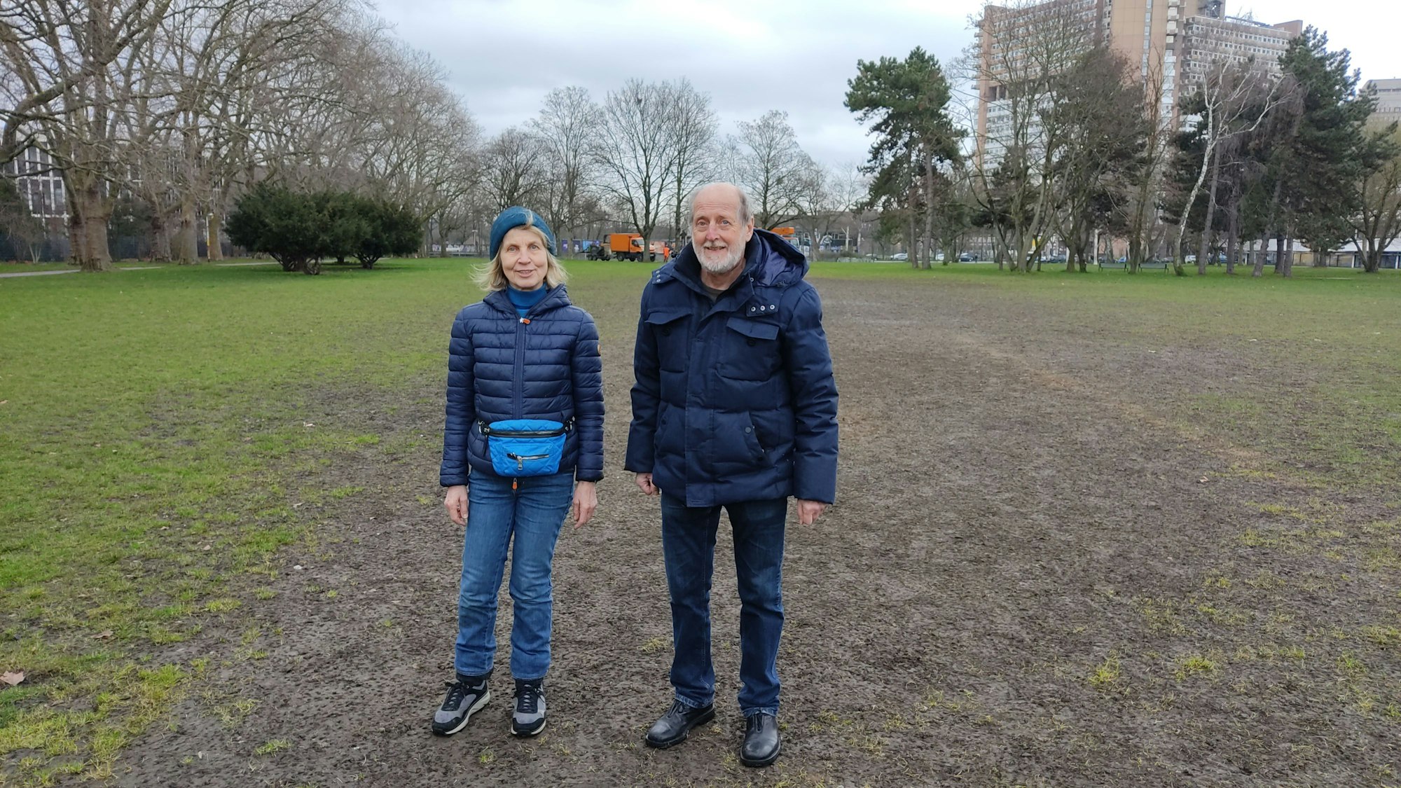 Anwohnerin Aleke Schücking und Helmut Röscheisen vom BUND stehen auf der Uniwiese, auf der ein großer braunes Loch klafft inmitten des Grüns klafft.