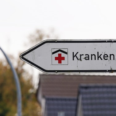 Ein Hinweisschild mit der Aufschrift „Krankenhaus“ weist an einer Straße den Weg zu einer Klinik.
