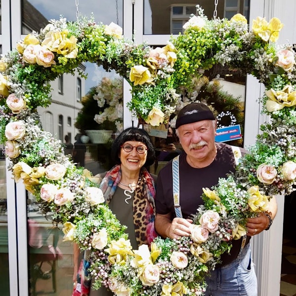 Geschi und Klaus Ridder mit einem großen Herz aus Blumen.