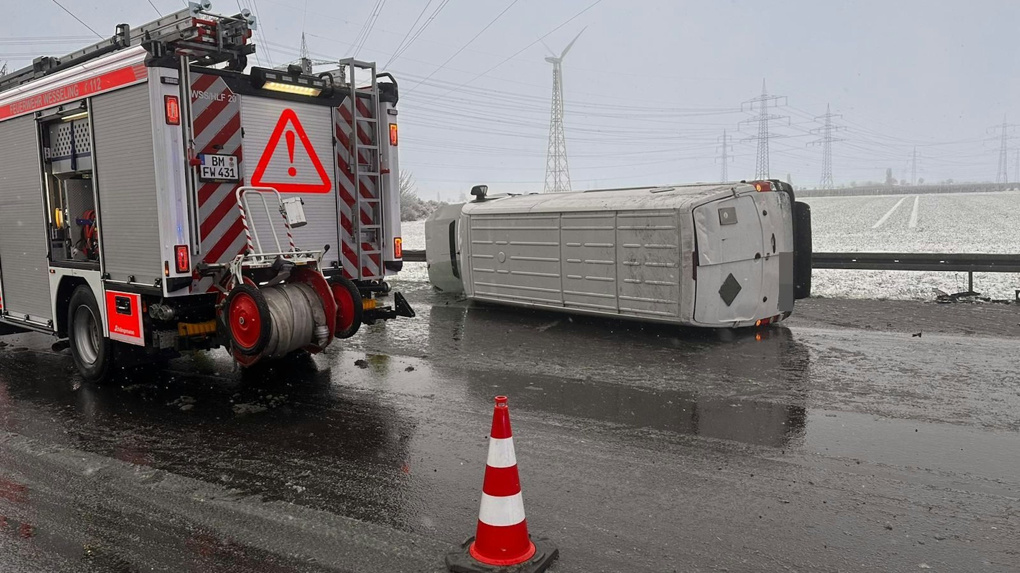 Ein Pakettransporter liegt seitlich auf der Fahrbahn. Daneben steht ein Feuerwehrauto.