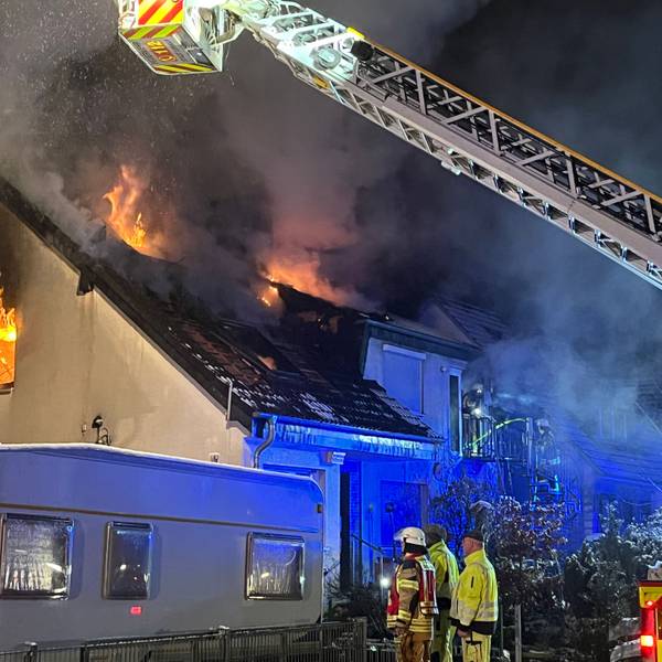 Feuer kommt aus den Fenstern im oberen Stockwerk eines Hauses