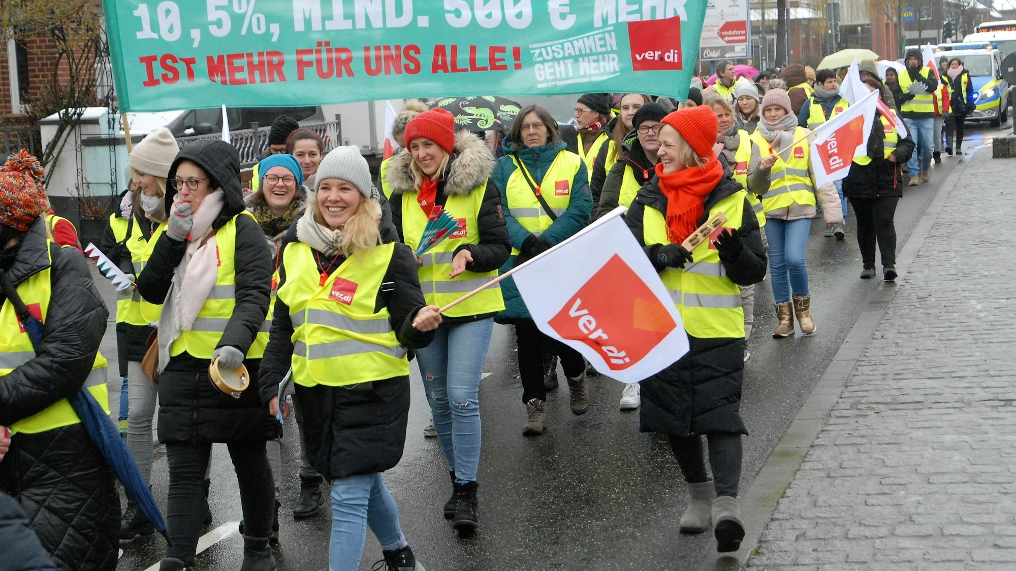 Auf dem Foto sind Beschäftigte des öffentlichen Dienstes in Kerpen bei einer Demonstration zu sehen. Sie tragen knallgelbe Westen der Gewerkschaften.
