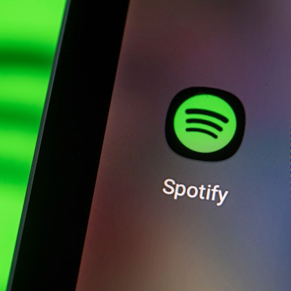 Auf dem Bildschirm eines Smartphones sieht man das Logo der App von Spotify.