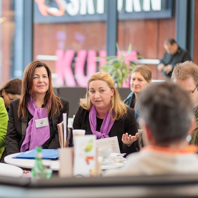 Drei Frauen sitzen bei einer Informationsveranstaltung nebeneinander.