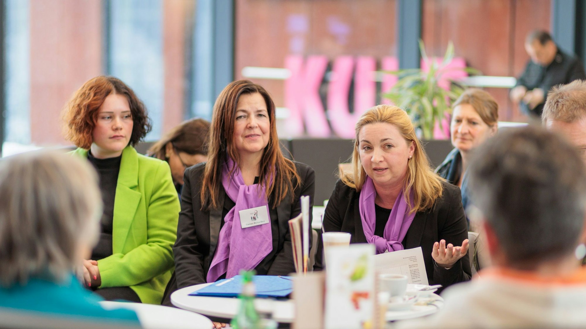 Drei Frauen sitzen bei einer Informationsveranstaltung nebeneinander.