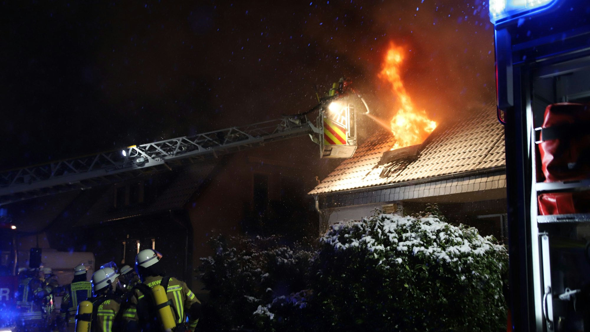 Die Feuerwehr versucht mithilfe einer Drehleiter an die Flammen im Obergeschoss zu kommen.