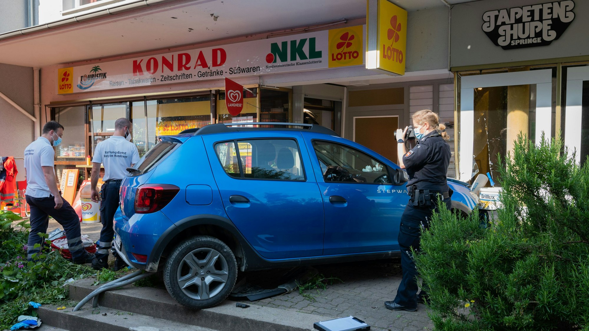 Einsatzkräfte von Rettungsdienst und Polizei stehen nach einem Unfall an einem Kleinwagen