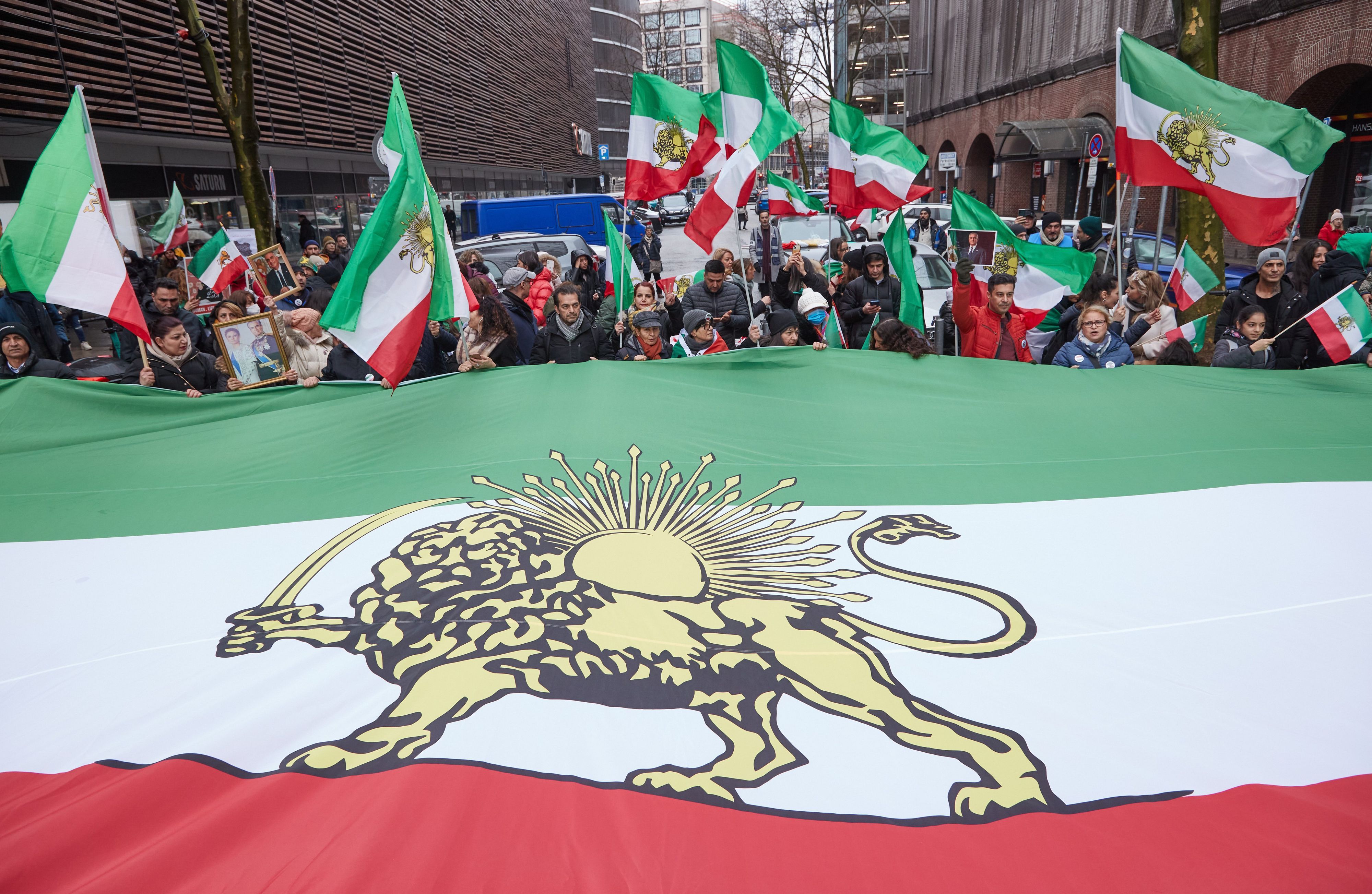 Teilnehmer einer Demonstration gegen das iranische Regime halten auf der Straße Lange Mühren einen überdimensionale iranische Flagge.