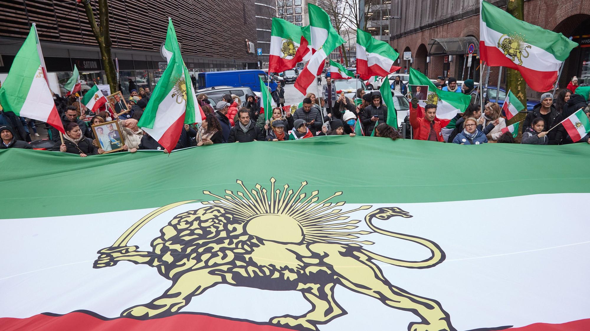 Teilnehmer einer Demonstration gegen das iranische Regime halten auf der Straße Lange Mühren einen überdimensionale iranische Flagge.