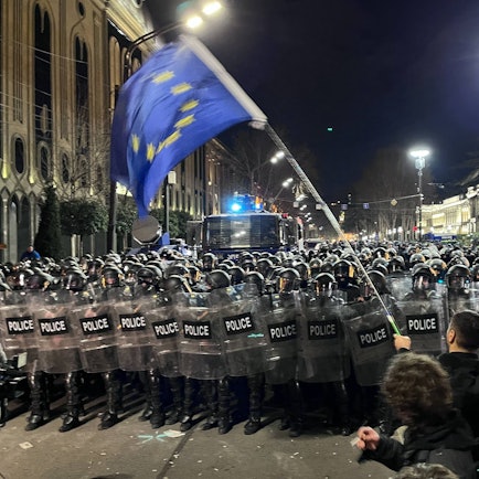 Ein Demonstrant, der eine EU-Flagge trägt, geht auf eine Polizeikette vor dem georgischen Parlamentsgebäude zu. Unter heftigem Protest aus der Bevölkerung ist in Georgien im Südkaukasus eine umstrittene Regelung über „ausländische Agenten“ auf den Weg gebracht worden.