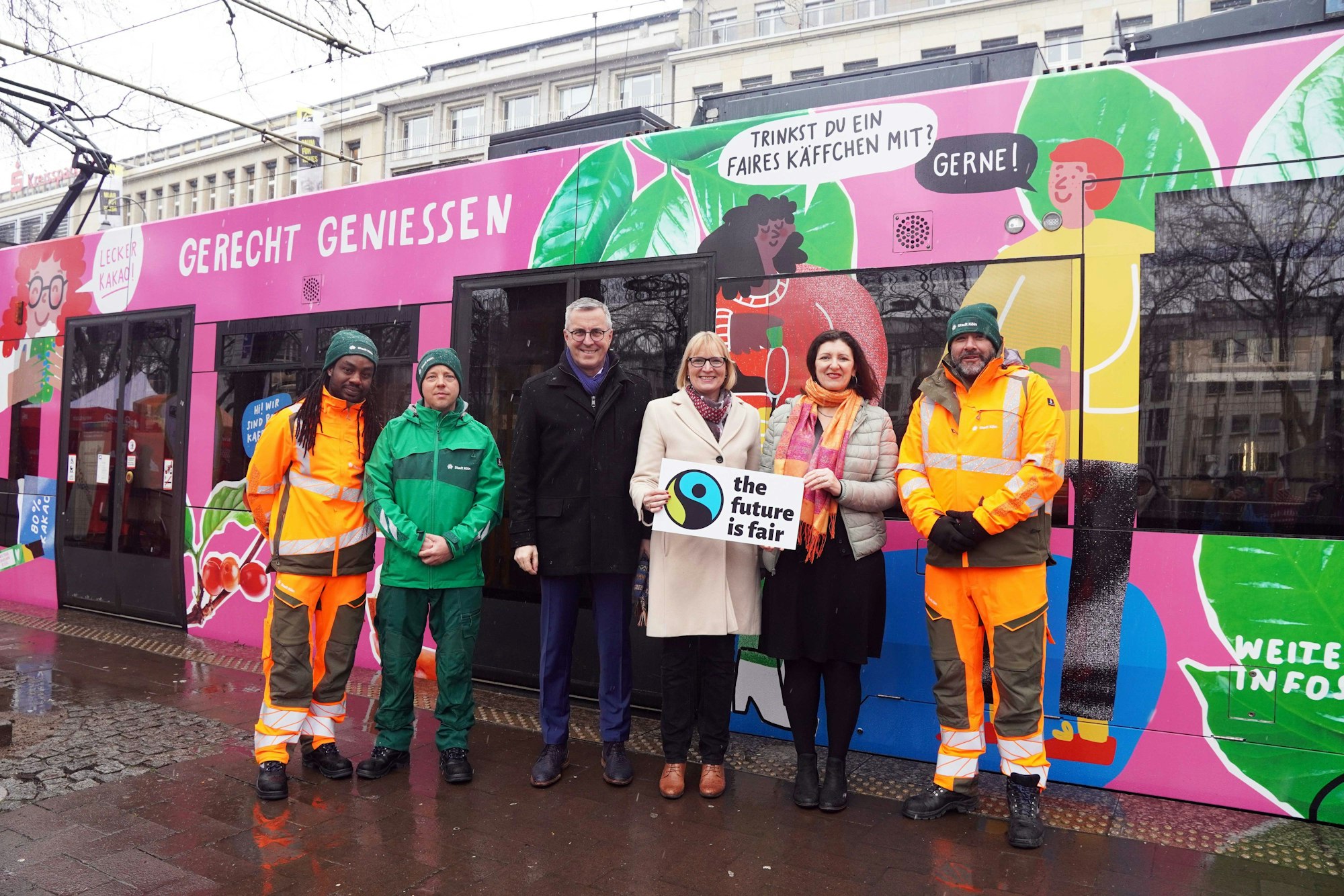 Sechs Personen stehen vor einer bunten KVB-Bahn, sie halten ein Schild mit der Aufschrift "The future is fair" in der Hand.