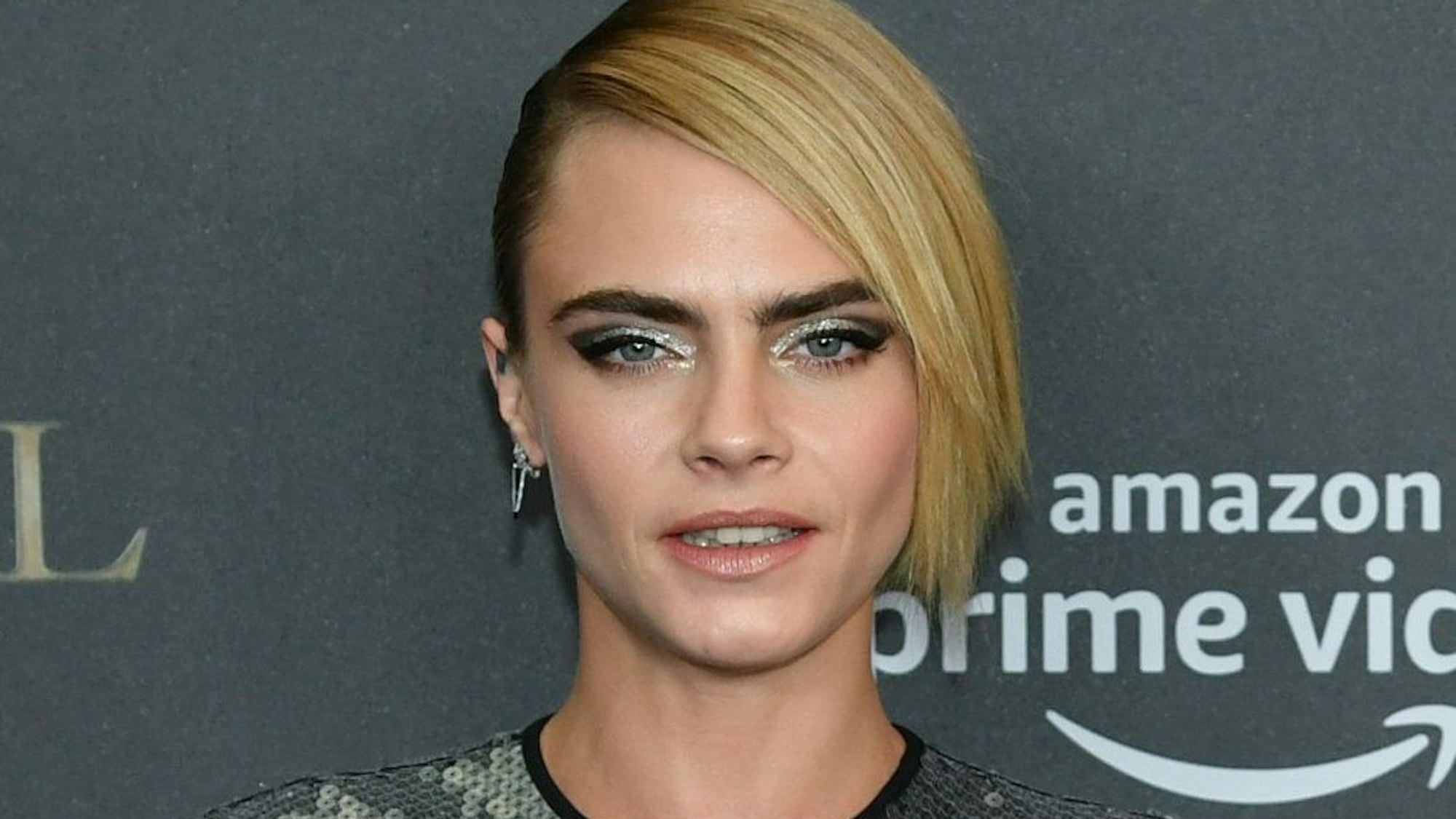Model Cara Delevingne bei einer Filmpremiere vor einer Wand.