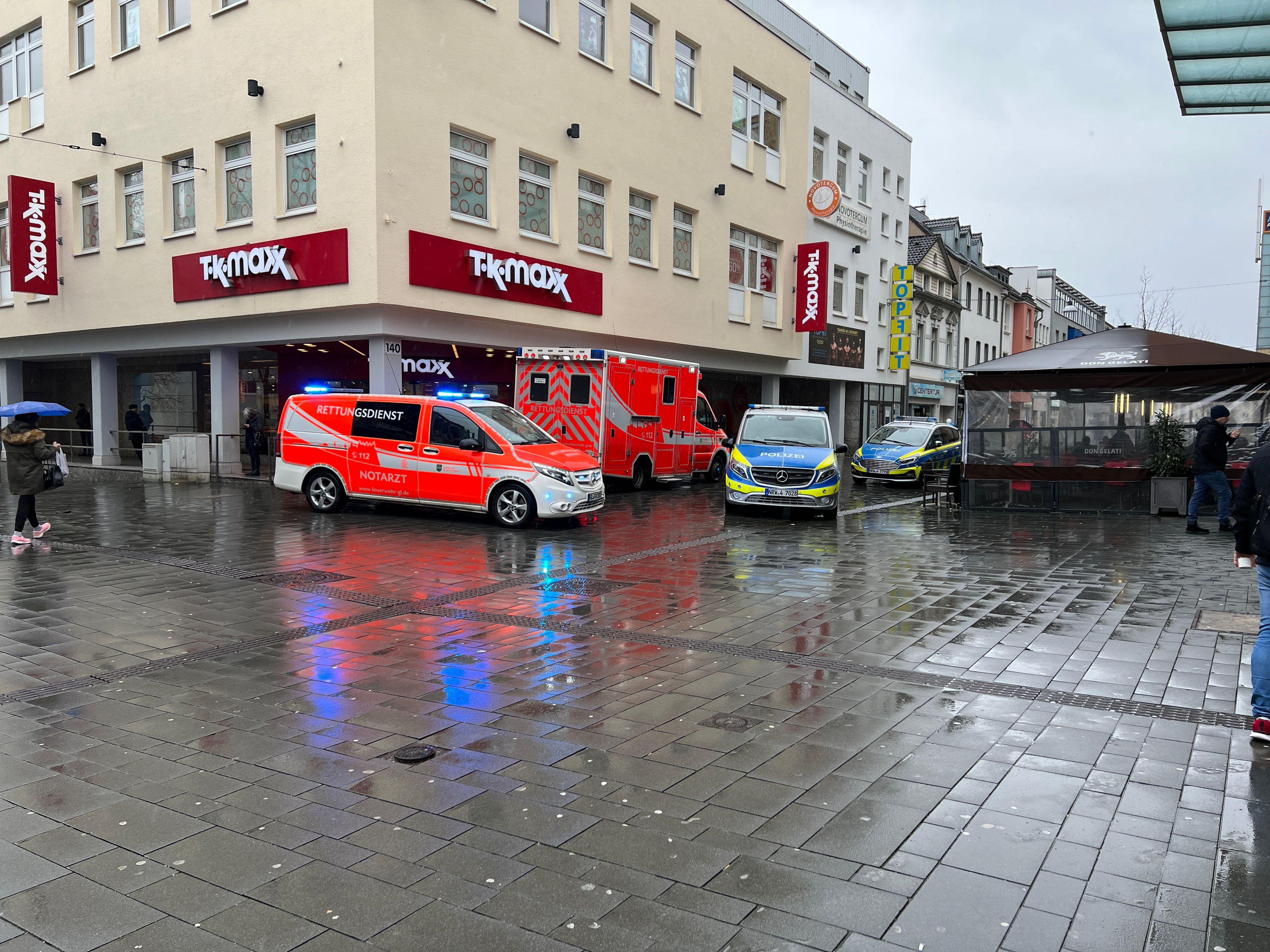 Fahrzeuge von Rettungsdienst und Polizei stehen vor einem Laden an der Gladbacher Fußgängerzone.