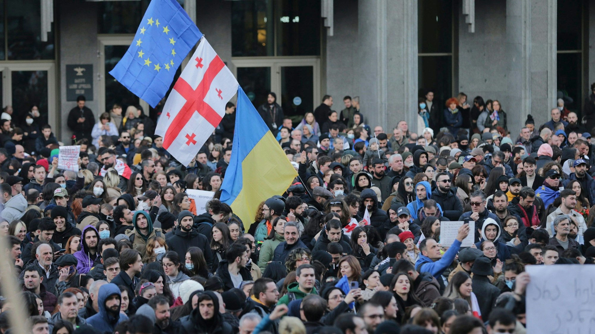 ARCHIV - 08.03.2023, Georgien, Tiflis: Demonstranten versammeln sich mit georgischen, ukrainischen und EU-Fahnen vor dem georgischen Parlamentsgebäude.