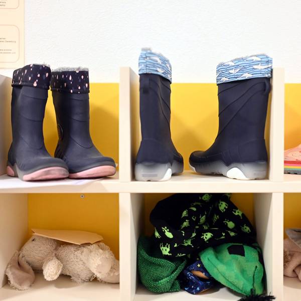 Kinderstiefel, ein Stofftier und Kinderkleidung sind in einem Regal untergebracht.
