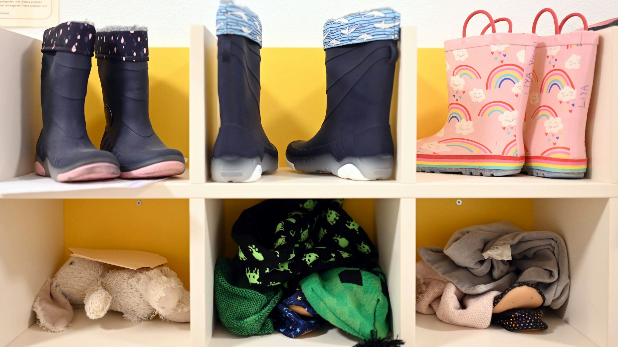 Kinderstiefel, ein Stofftier und Kinderkleidung sind in einem Regal untergebracht.