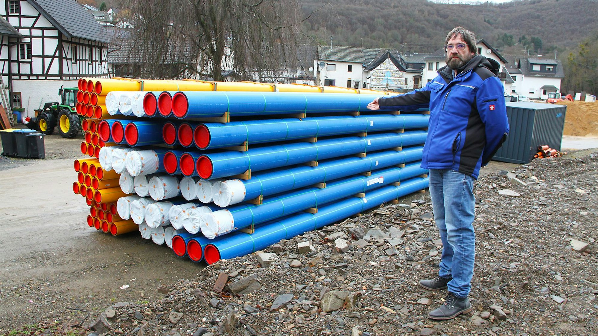 Ein Mann steht vor einem Stapel blauer und gelber Rohre.