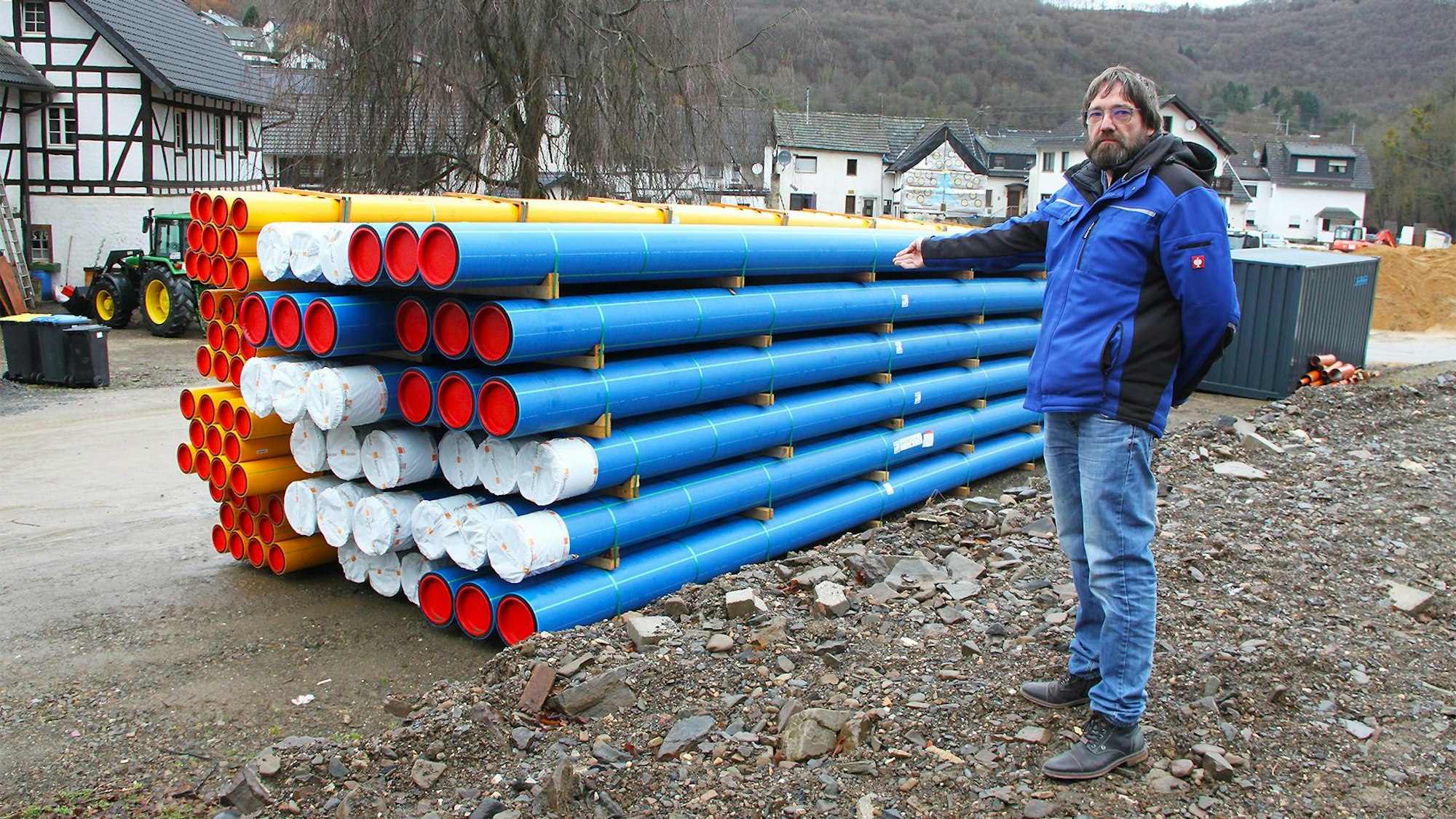 Ein Mann steht vor einem Stapel blauer und gelber Rohre.