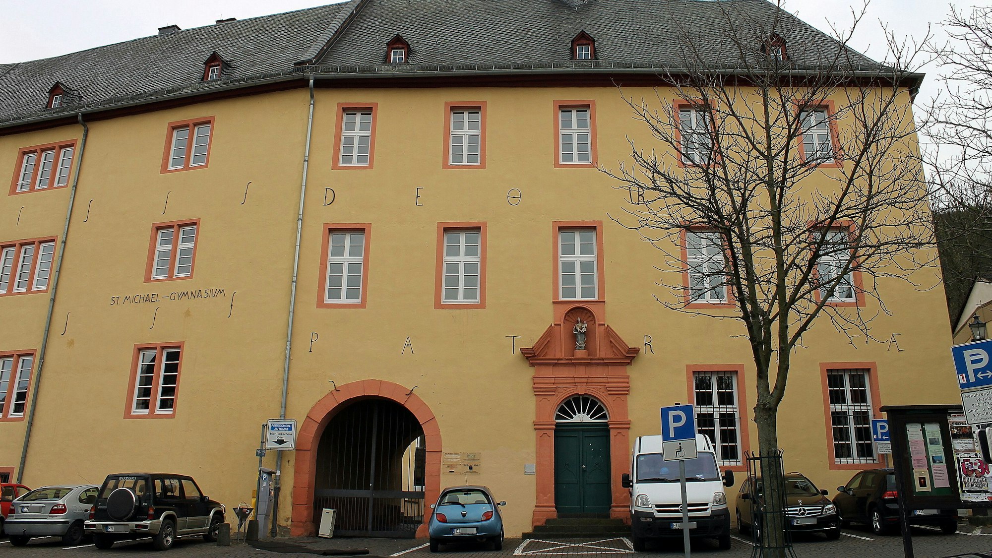 Das Bild zeigt die Außenansicht des St.-Michael-Gymnasiums vom Salzmarkt aus. Vor dem Gebäude parken Fahrzeuge.