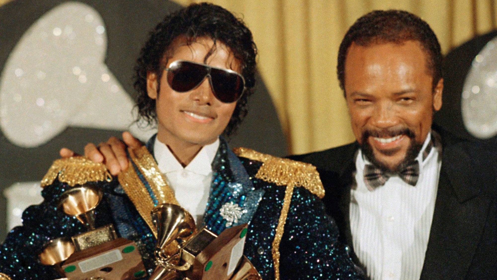 Michael Jackson (l) und sein langjähriger Produzent Quincy Jones stehen mit Grammy-Trophäen bei der Verleihung der Grammy Awards im Jahr 1984 nebeneinander.