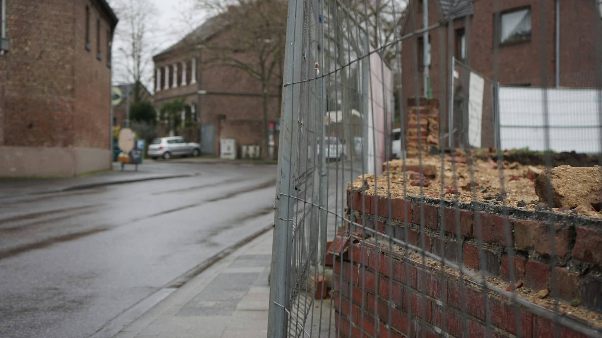 Mauer von abgerissenem Hof auf der Erftstraße in Kerpen-Sindorf, umgeben von Bauzaun.