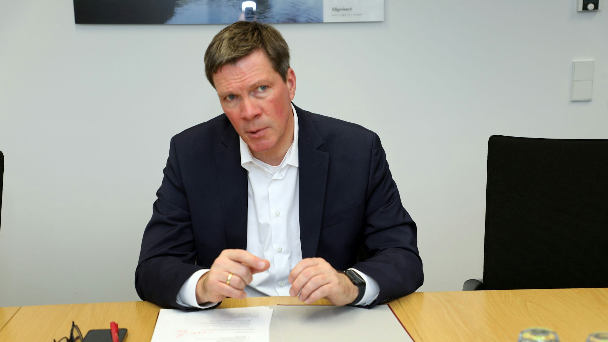 Stephan Santelmann, Landrat des Rheinisch-Bergischen Kreises, sitzt an einem Tisch.