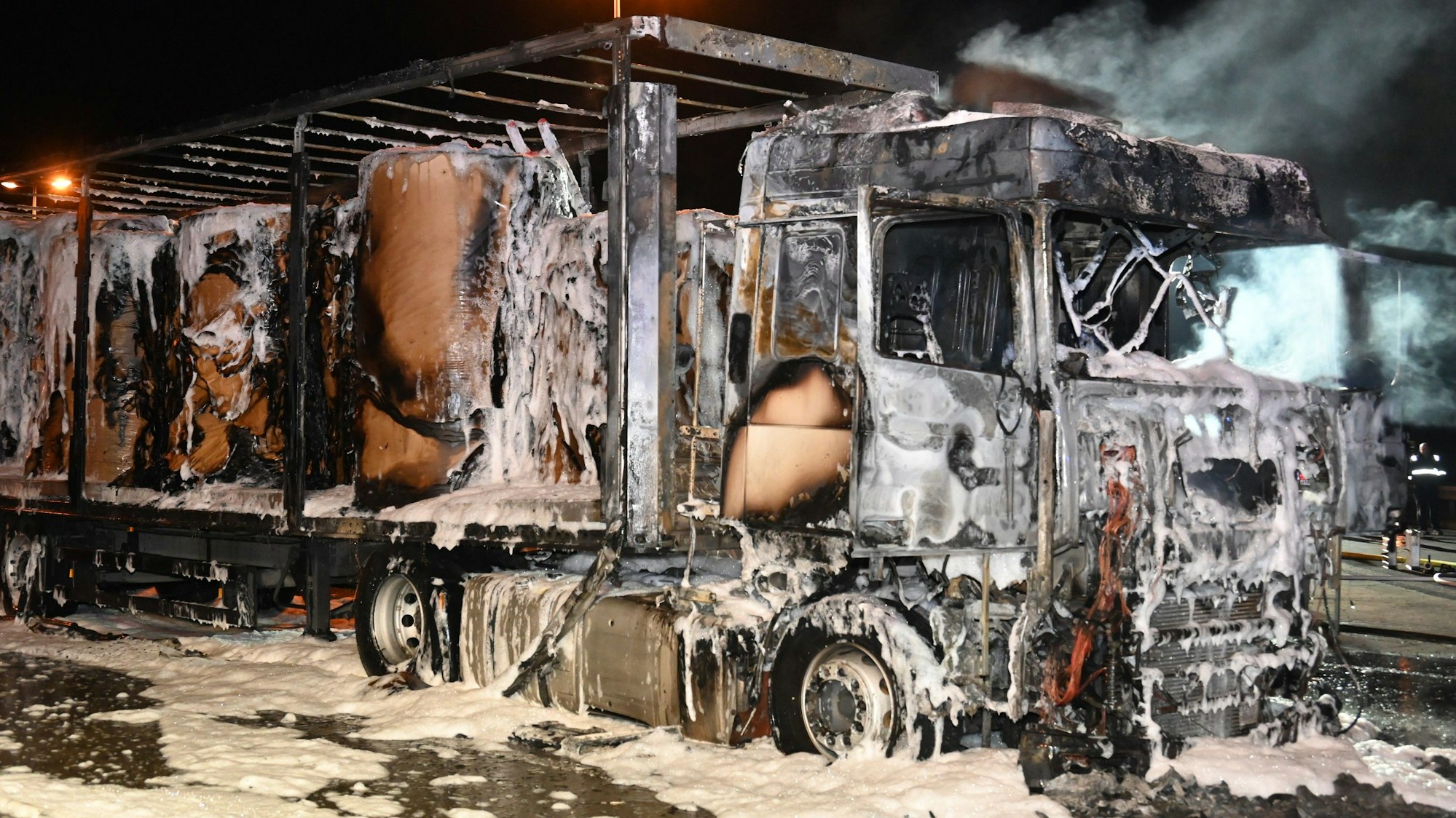 Man sieht ein ausgebranntes Wrack eines Lkw.