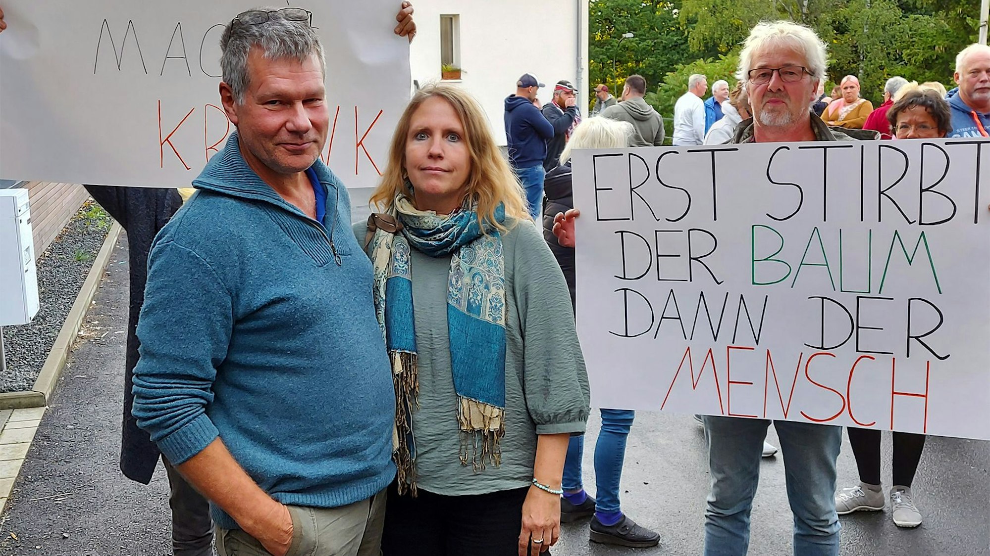 Einige Menschen protestieren mit Plakaten gegen den Bau eines Feriendorfs am Freilinger See.