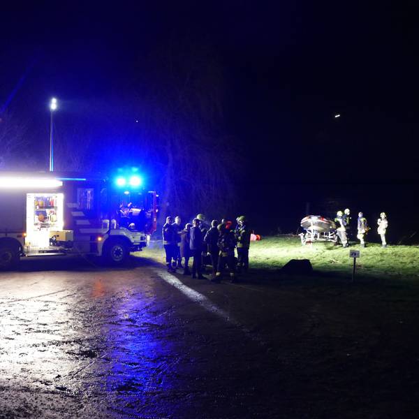 Am nächtlichen Siegufer stehen ein Feuerwehrauto und Feuerwehrleute, auch ein Schlauchboot ist am Ufer.