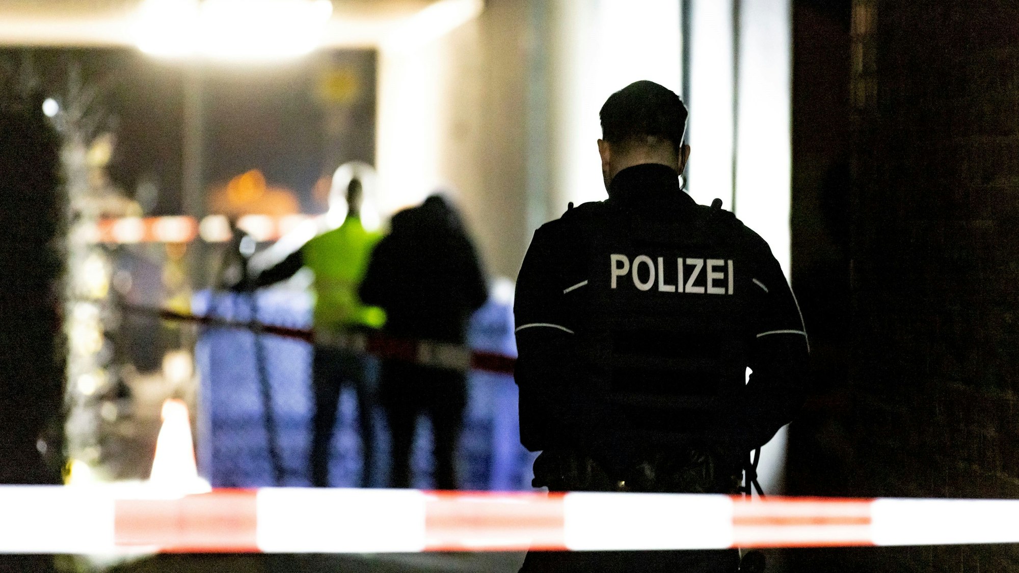 Ein Polizist steht hinter einem Absperrband der Polizei.