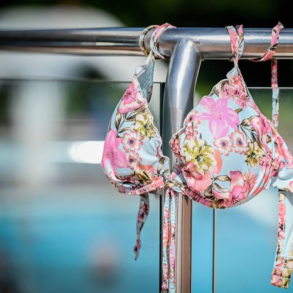 Ein Bikinioberteil hängt an einem Schwimmbad-Geländer.