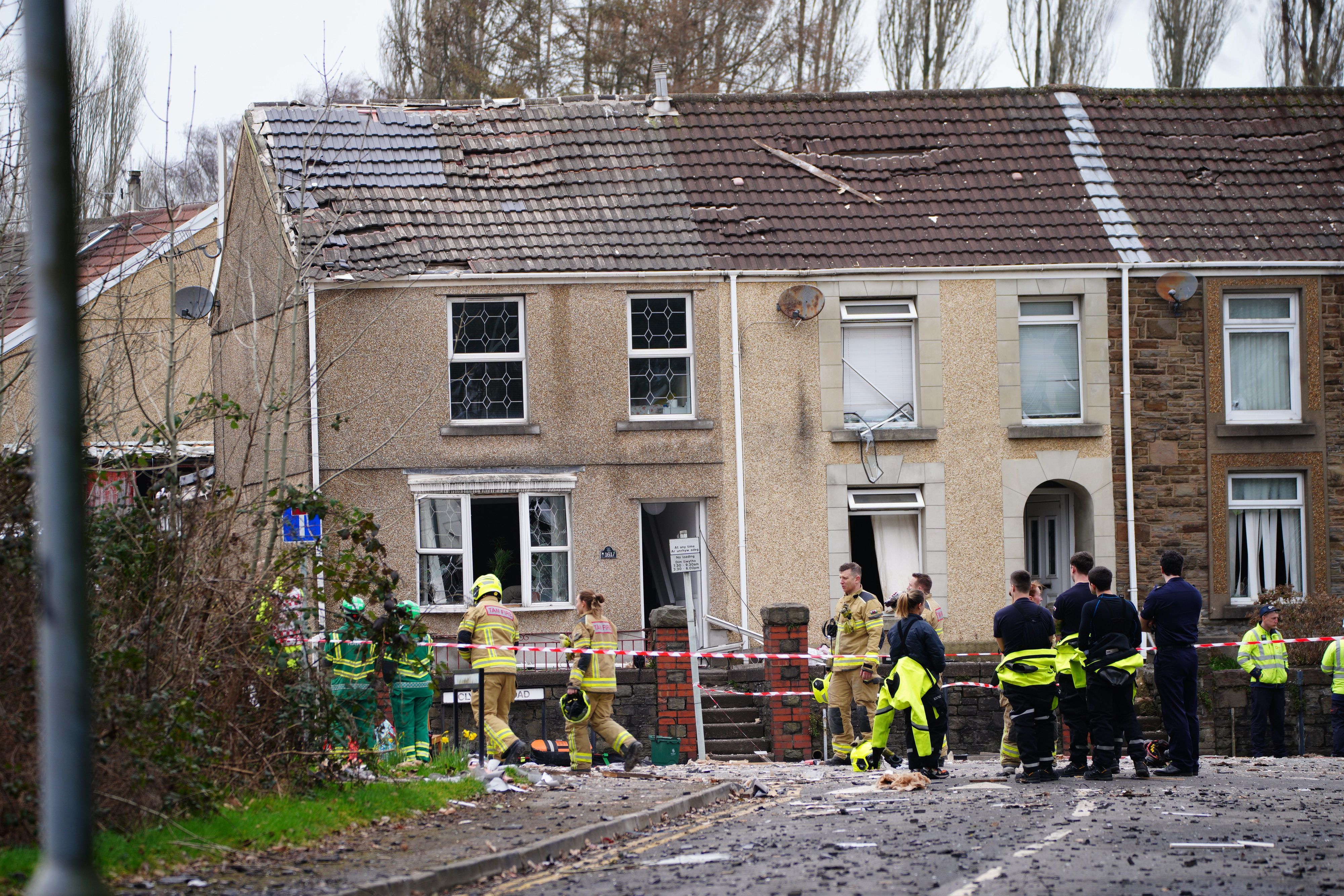 Einsatzkräfte stehen nach einer schweren Detonation vor zwei zerstörten Häusern an einer Straßenkreuzung in Morriston.