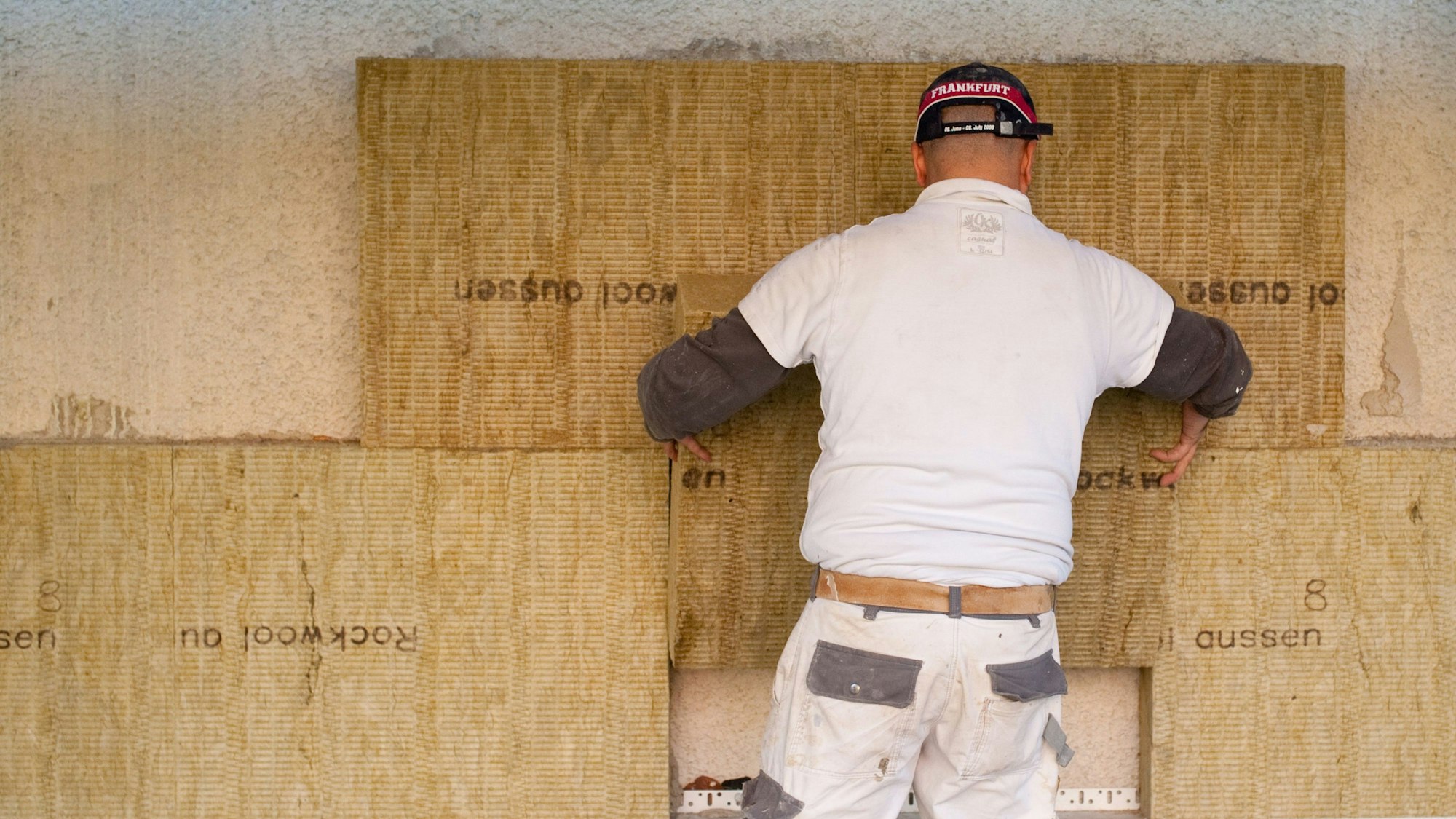 Ein Mann bringt Dämmmaterial an einer Wand an.